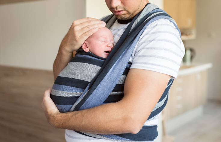 baby in a sling with father